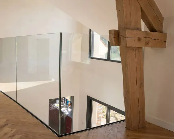 Mezzanine intérieure avec garde-corps verre et poutre bois